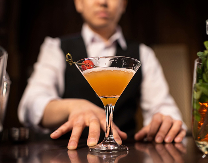 Bartender serving a cocktail in a martini glass at Fox Resorts